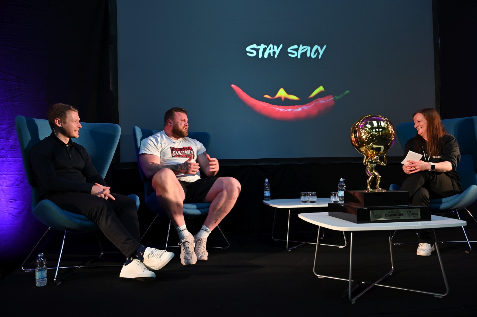 Three people sitting on chairs on a stage