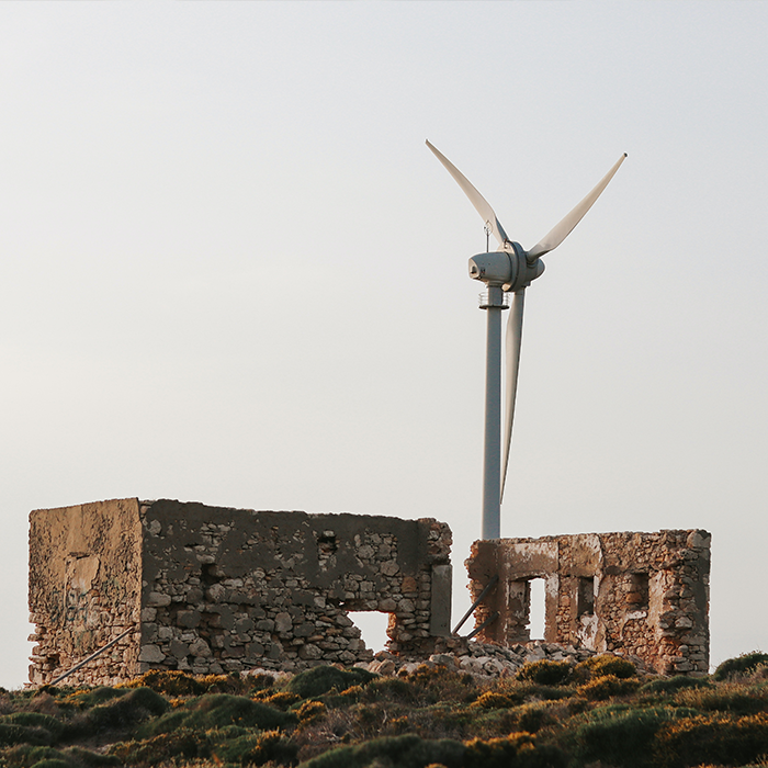 Wind turbine next to broken down building.