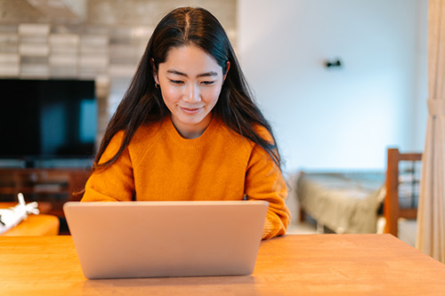 student in orange using laptop